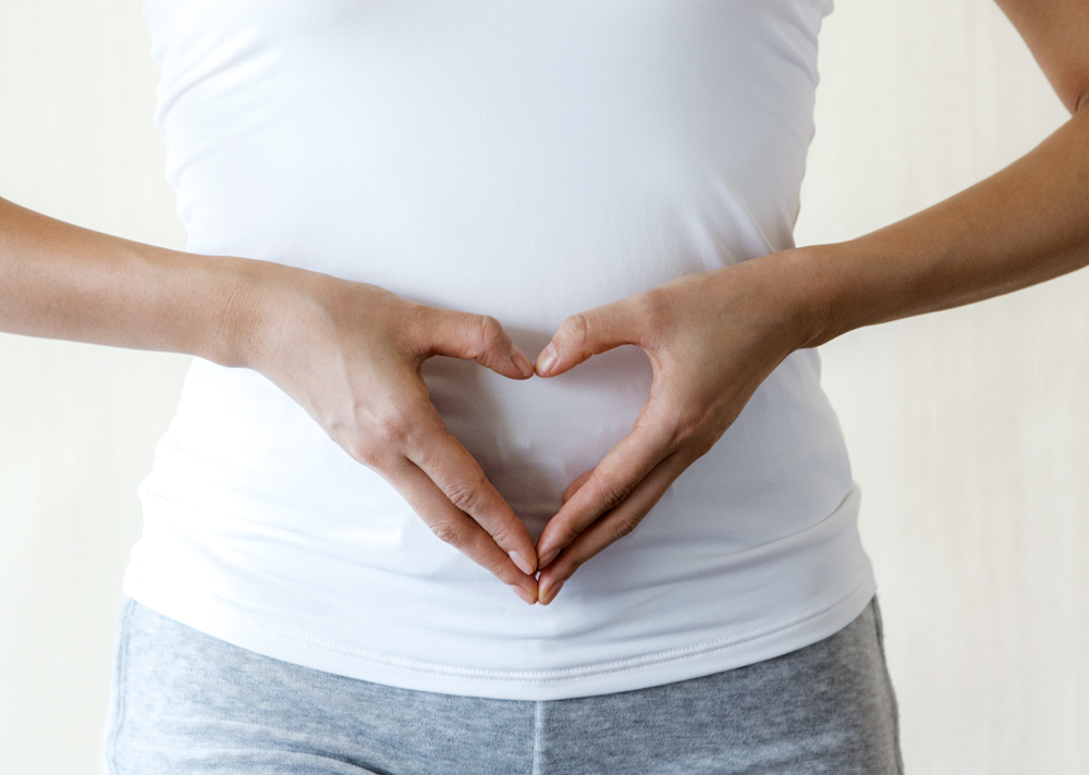 Hände formen ein Herz vor dem Bauch