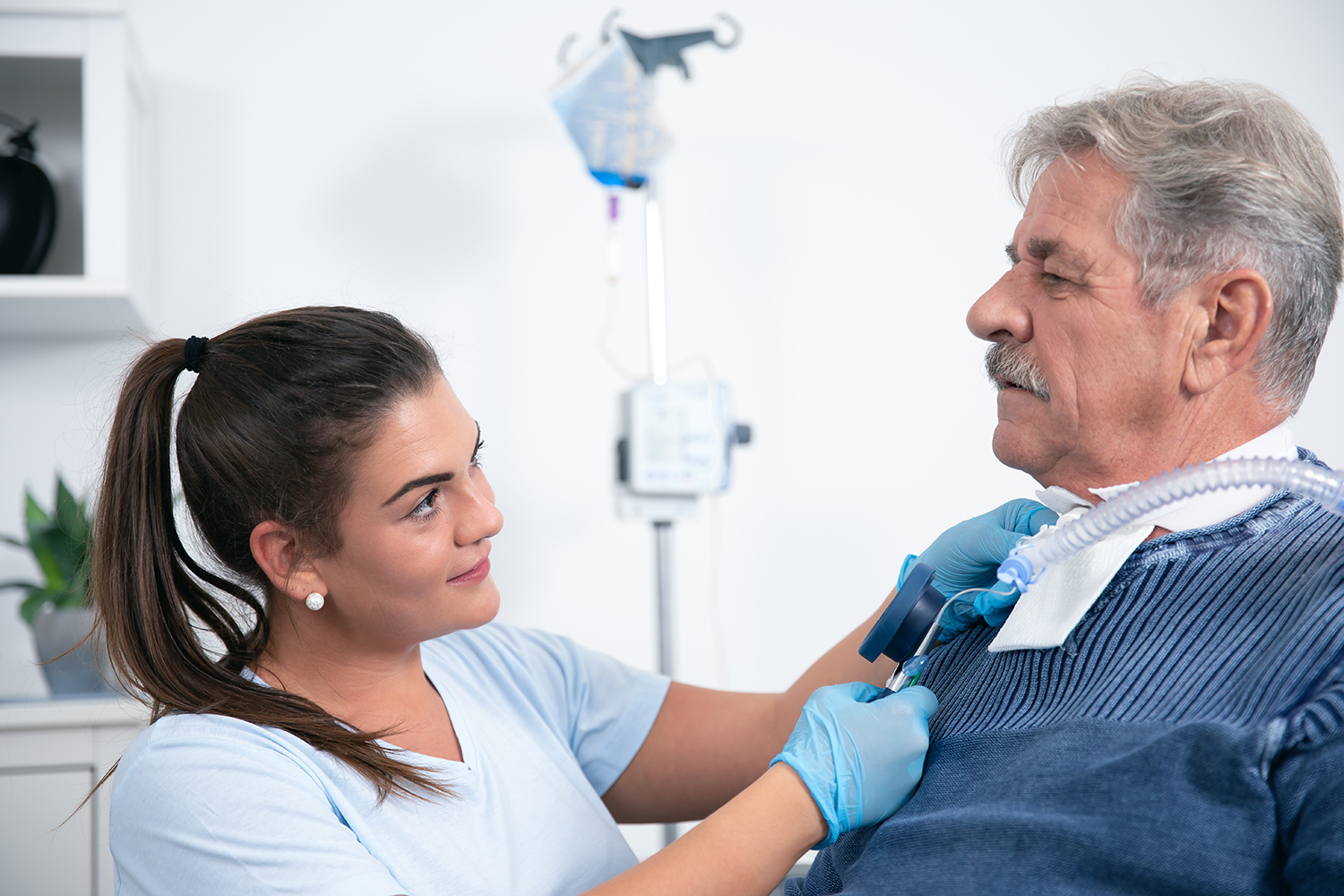 Pflegekraft kontrolliert den Tracheostoma eines Patienten